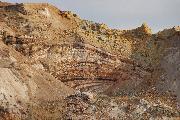 Ein baumkuchenartiges Schichtungsgebilde aus den kreidezeitlichen hydrothermalen Meeresbodenablagerungen im Anschnitt, darüber Minenabraum (Oktober 2009).
